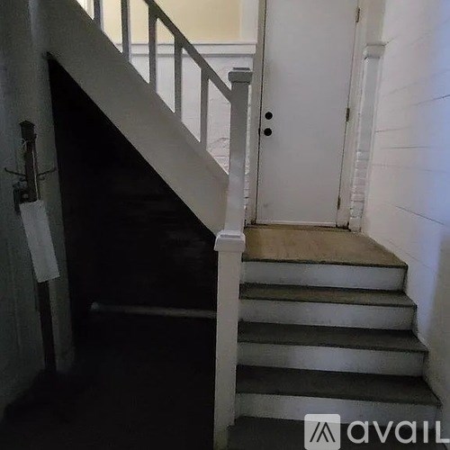 A staircase with a white railing and a white door at the top.