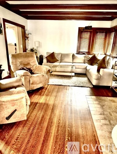 A living room with a wooden floor and white furniture.