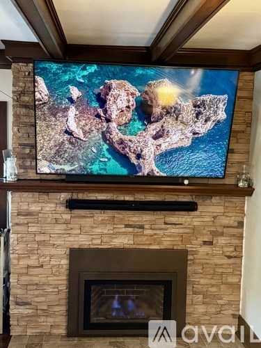 A large screen TV mounted above a fireplace.