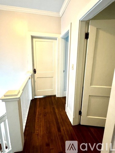A hallway with a white door and a white railing.