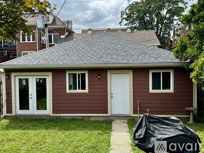 A small house with a white door and windows is covered in a black tarp.