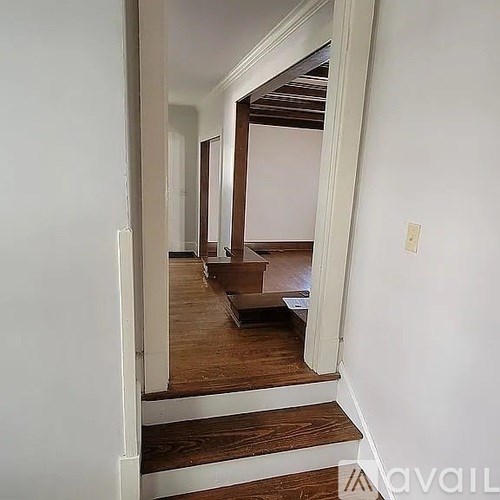 A hallway with a wooden floor and white walls.