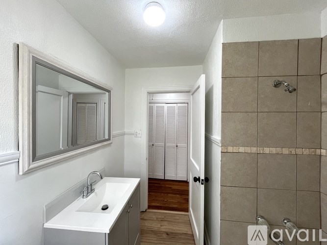 A bathroom with a sink, mirror, and shower.
