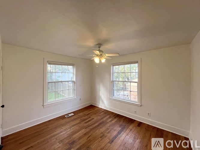 A room with wooden floors and two windows.