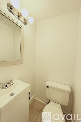 A white toilet in a bathroom with a sink and mirror.
