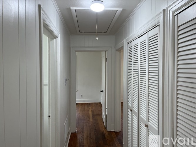 A long hallway with white walls and wood floors.