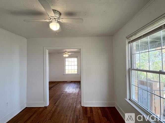 A room with wooden floors and a ceiling fan with a light on.