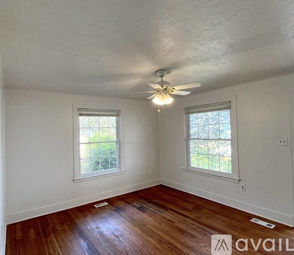 A room with wooden floors and two windows.