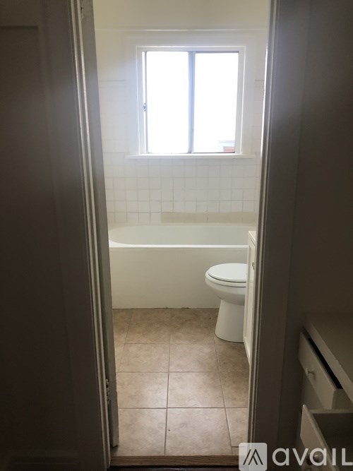 A bathroom with a toilet, tub, and window.