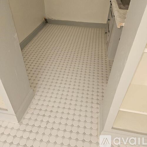 A bathroom with a white tiled floor and white walls.