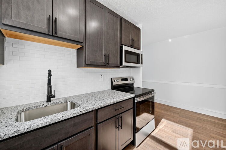 A kitchen with dark wood cabinets and a granite countertop.