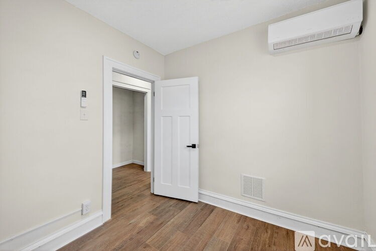 A room with a white door and a wall-mounted air conditioner.