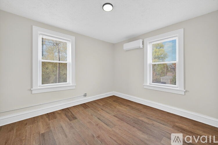 A room with two windows and wooden flooring.