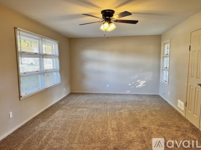 A room with a ceiling fan and carpeted floor.