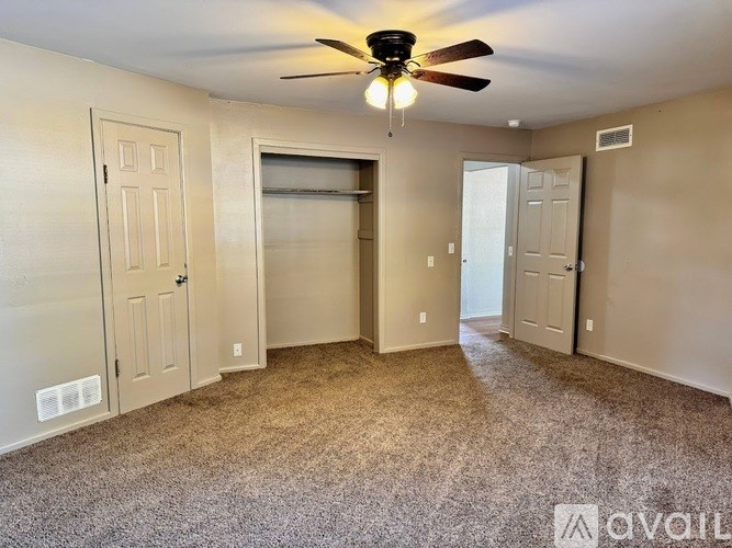 A room with a ceiling fan and carpeted floor.