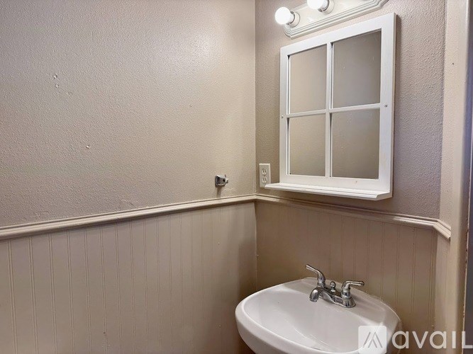 A white sink in a bathroom with a window above it.