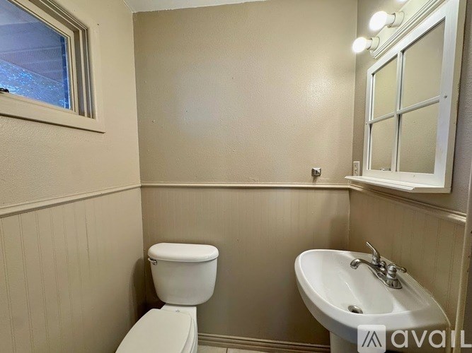 A bathroom with a toilet, sink, and window.