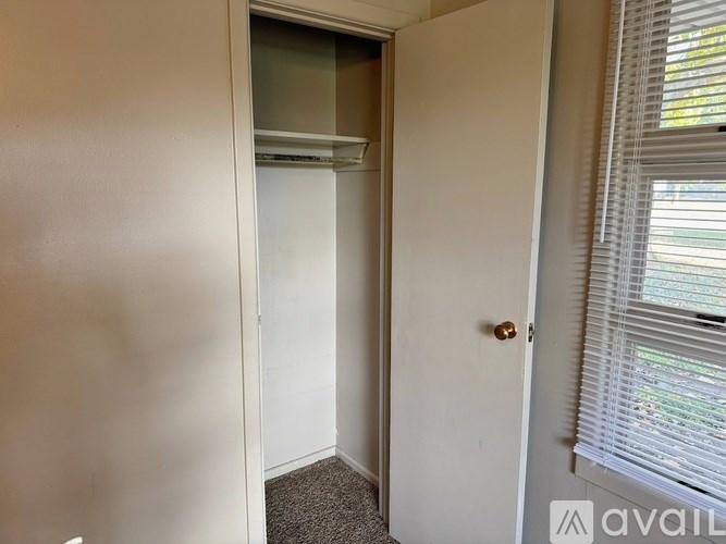 A small, empty room with a door and a window with blinds.