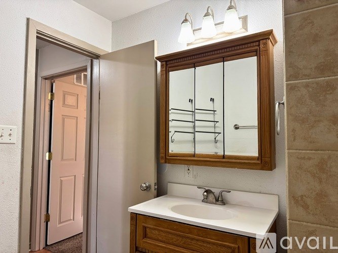 A bathroom with a sink, mirror, and a door.