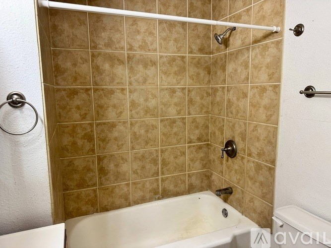 A tiled shower area with a white tub and a white shower curtain.