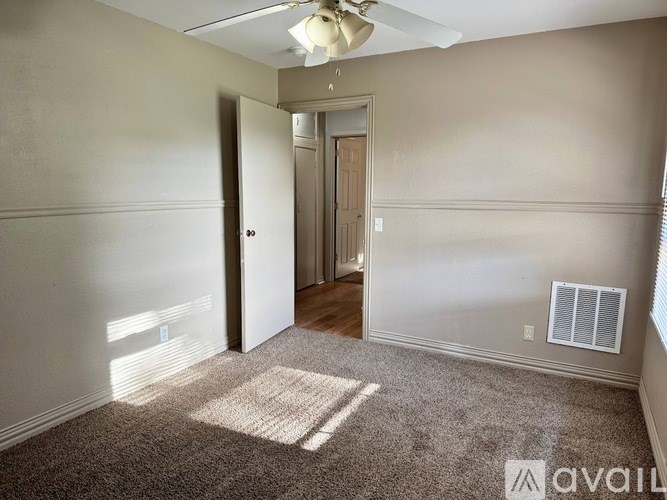 A room with a carpeted floor and a ceiling fan.