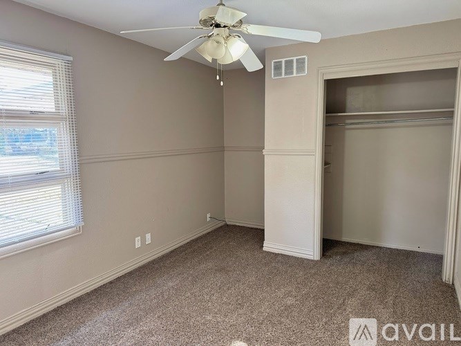 A room with a ceiling fan and a window with blinds.