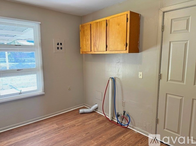 A room with wooden floors and a window with blinds.