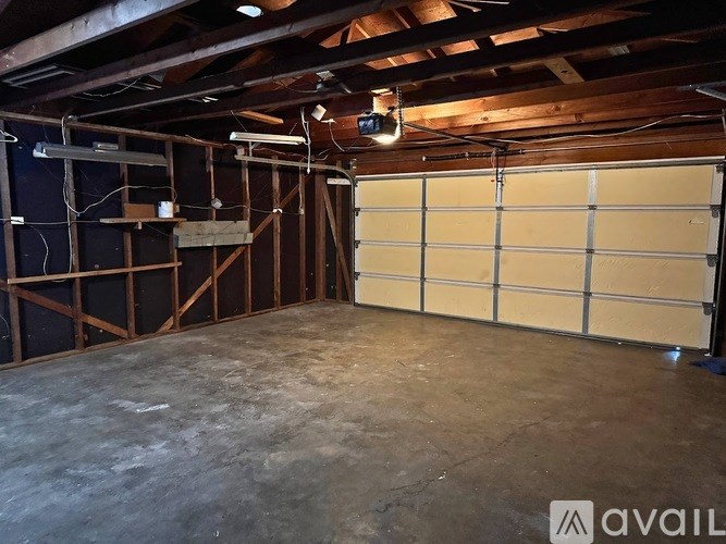 A large empty garage with a wooden ceiling and a white door.