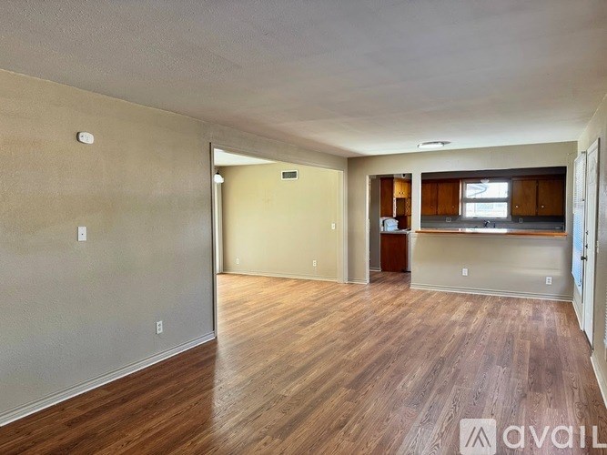 A spacious room with wooden flooring and a wall-mounted light fixture.