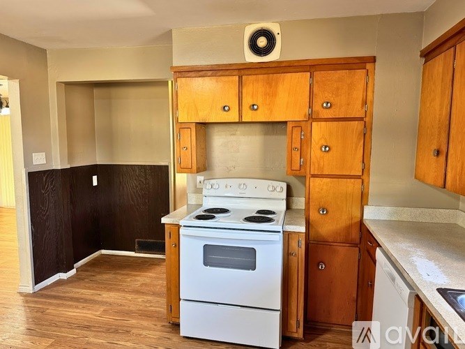A kitchen with a white stove and wooden cabinets.