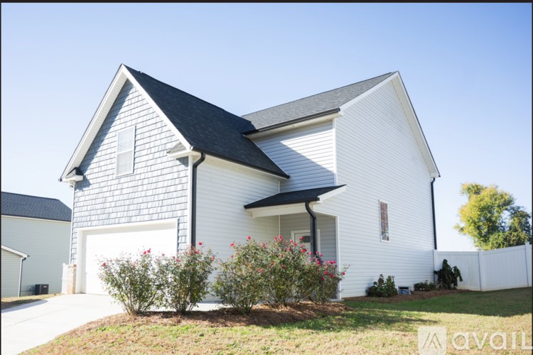 A white house with a black roof and a garage door.