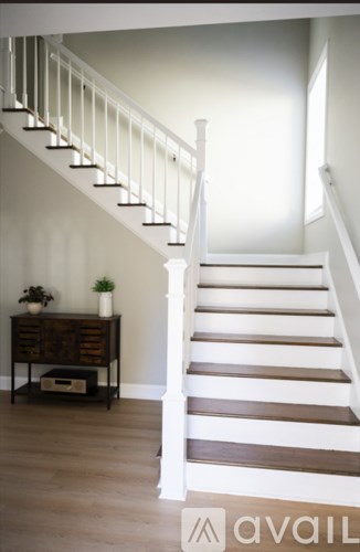 A wooden staircase with a white railing and a wooden table with a plant on it.