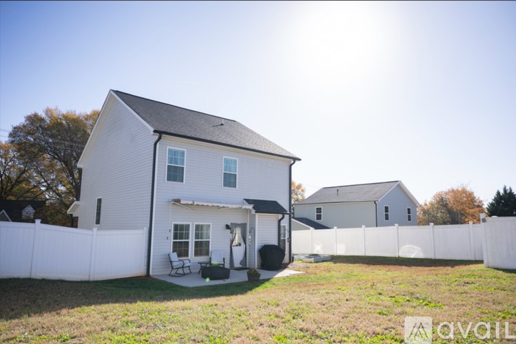 A white house with a black roof and a white fence.
