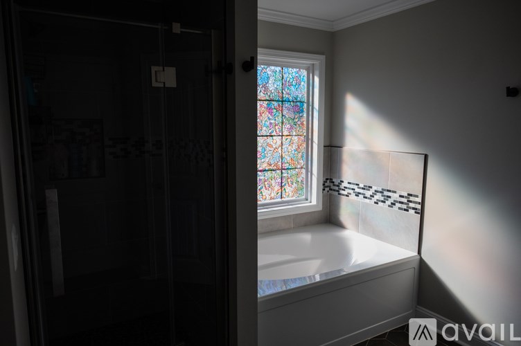 A bathroom with a tub and a window with a stained glass design.