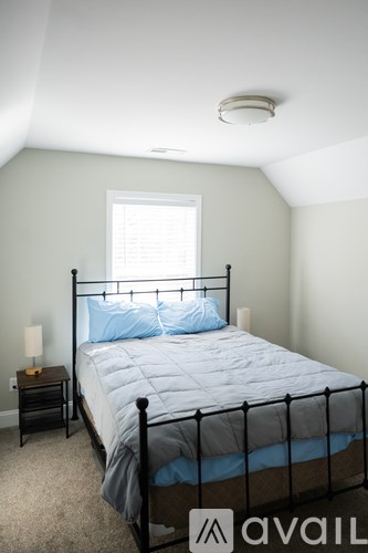 A bedroom with a bed, nightstand, and window.
