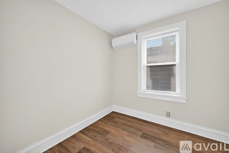 A room with a window and a wall-mounted air conditioner.