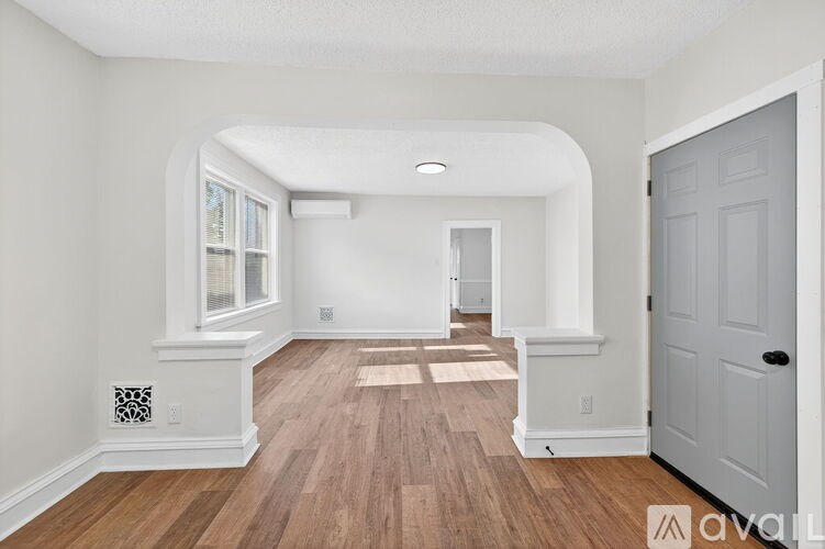 A white interior room with wooden floors and a white door.