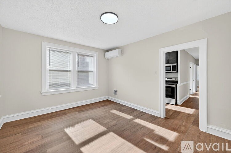 A room with a window and a door leading to a kitchen.