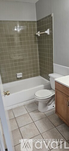 A bathroom with a toilet, tub, and tiled walls.