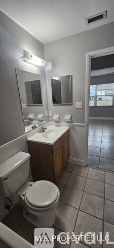 A bathroom with a toilet, sink, and mirror.
