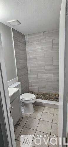 A bathroom with a toilet, sink, and tiled walls.