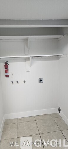 A white wall with a fire extinguisher on it.