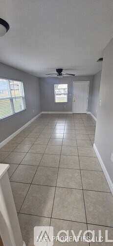 A spacious room with a ceiling fan and tiled flooring.