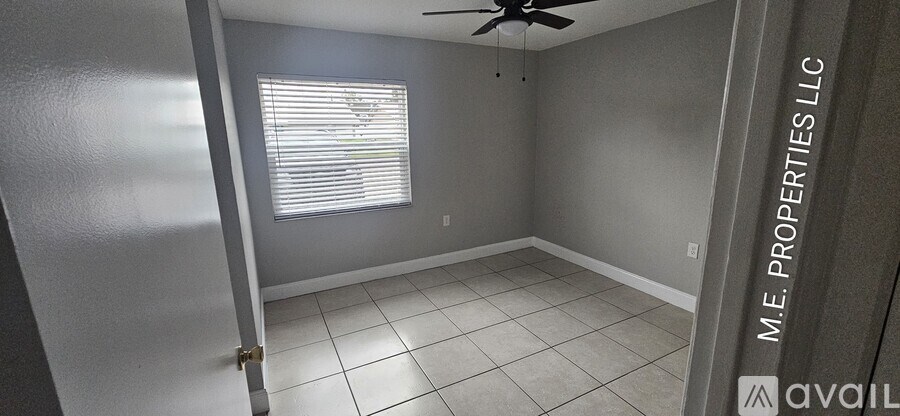 A room with a fan and a window with blinds.