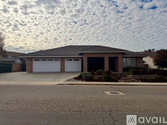 A house with a cracked driveway and a cloudy sky in the background.