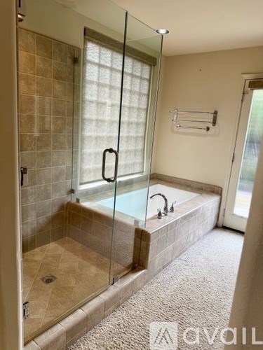 A bathroom with a glass shower door and a glass-enclosed bathtub.