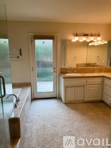 A well-lit kitchen with a carpeted floor and a glass door.