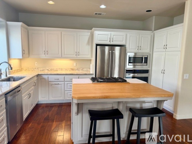 A kitchen with white cabinets and a wooden island.