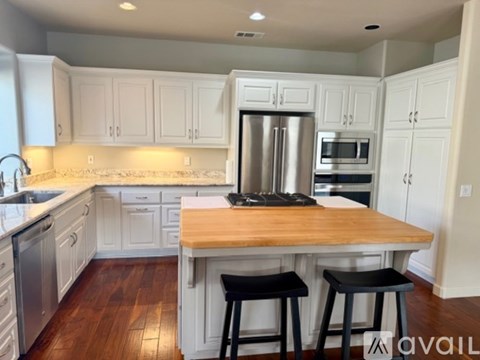 A kitchen with white cabinets and a wooden island.