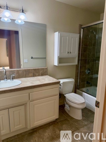 A bathroom with a sink, toilet and cabinet.